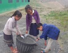 Three girls pick up rubbish and put it in a basket. 